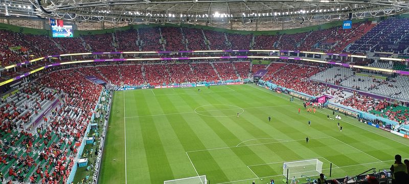 View from the upper tier of Al Thumama Stadium across the pitch to the stands and roof on a match night