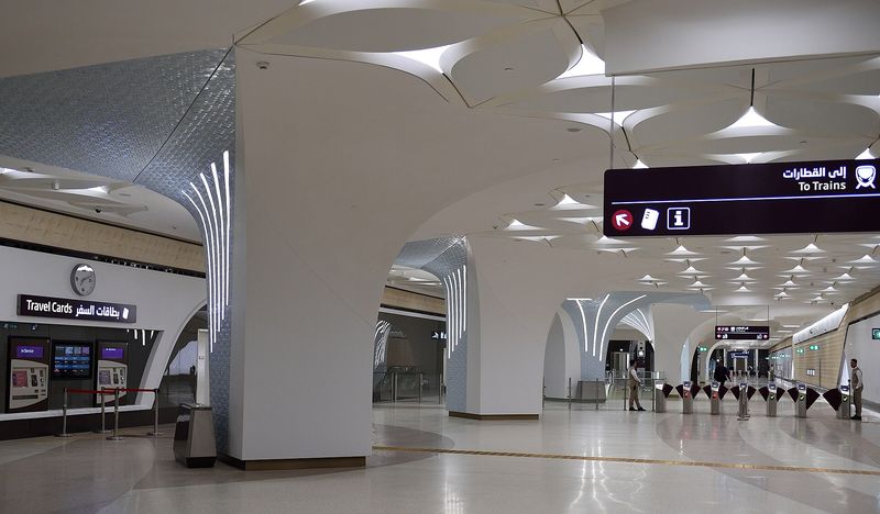 Ticket gates and white vaulted ceiling inside a Doha Metro station concourse