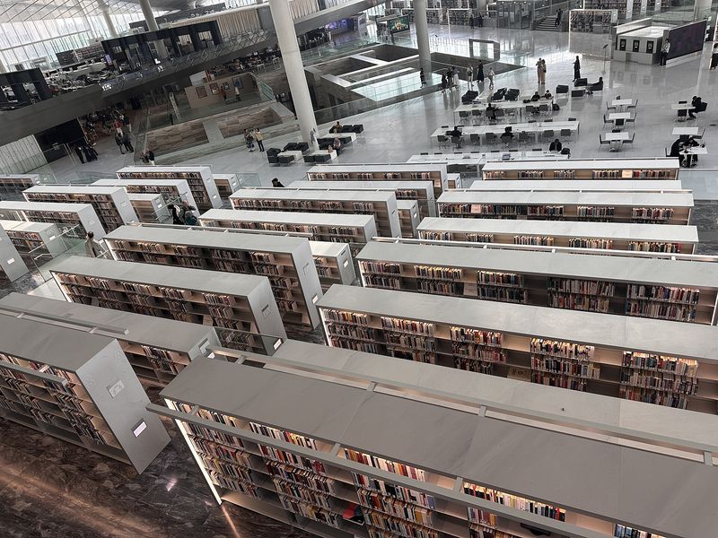 Rows of white bookshelves seen from above inside the Qatar National Library