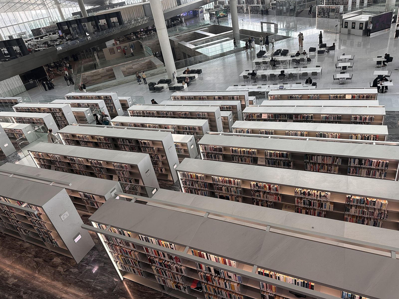 Rows of white bookshelves seen from above inside the Qatar National Library