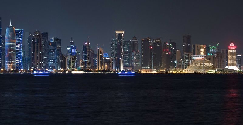 Doha's West Bay skyline lit up at night and reflected in the dark water of Doha Bay
